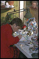 An artist painting a plate in a carnival mask shop